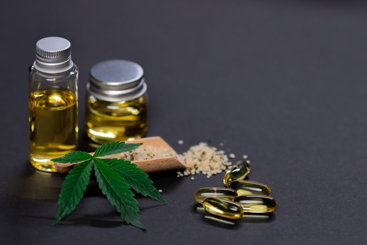 Frascos de óleo de canabidiol e cápsulas de CBD em fundo escuro